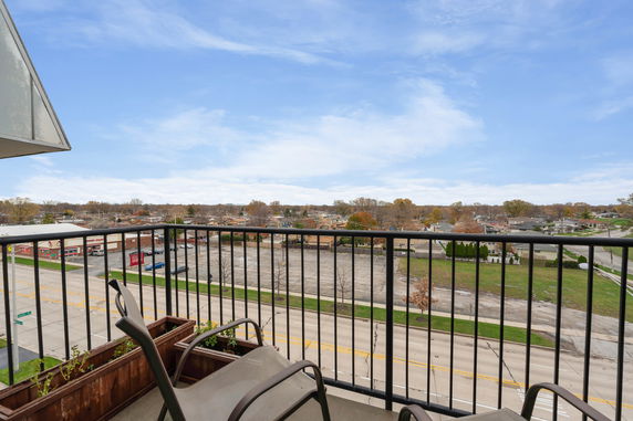 Panoramic view from a balcony overlooking a road and surrounding neighborhood.