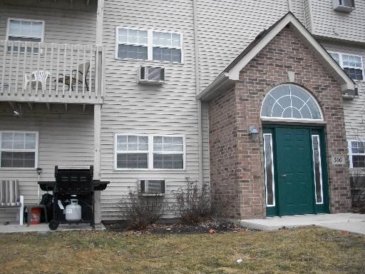 Front view of a multi-story residential building with a green door and balconies.