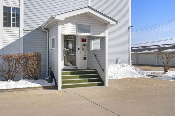 Front view of building entrance with steps and a glass door.
