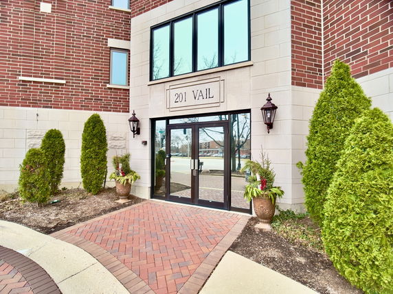 Front view of a brick building entrance with decorative plants.