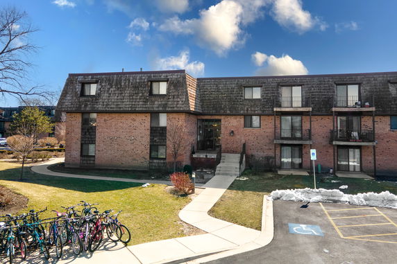 Front view of a brick residential building with multiple balconies and an entrance walkway.