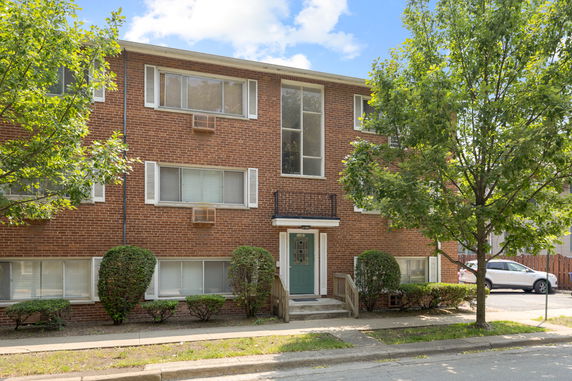 Front view of a three-story brick building with a central entrance and large windows.