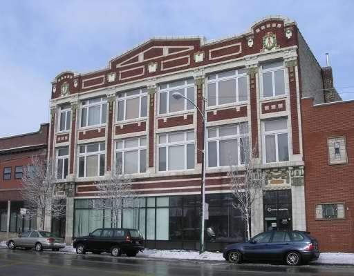 Front view of a multi-story brick building with large windows and decorative elements.