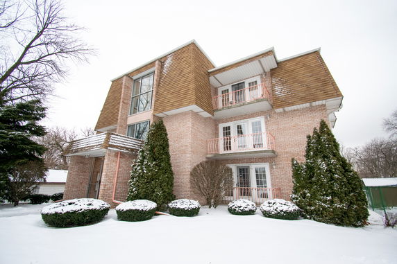 Front view of a multi-story house with balconies and a brick exterior.