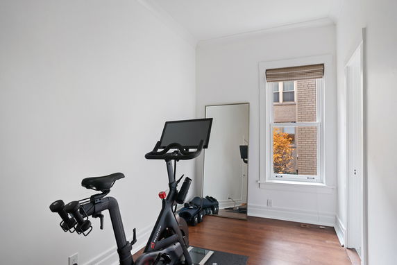 A room with an exercise bike and a mirror by the window.