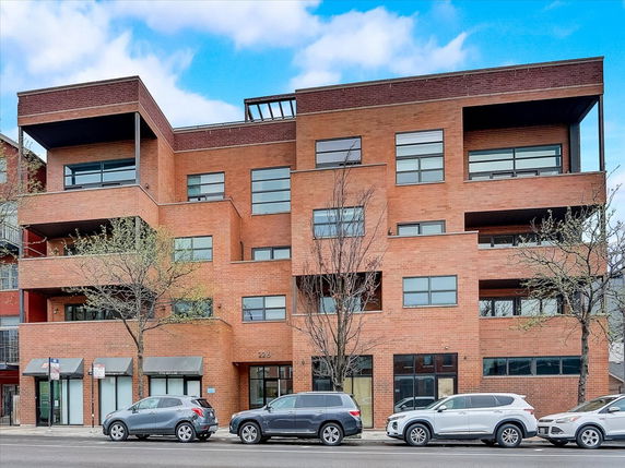 Front view of a multi-story brick building with balconies and large windows.