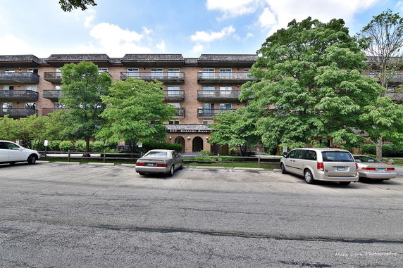 Front view of a multi-story residential building with balconies and parking area.