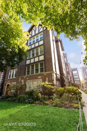 Front view of a tall brick building with multiple windows and decorative elements.