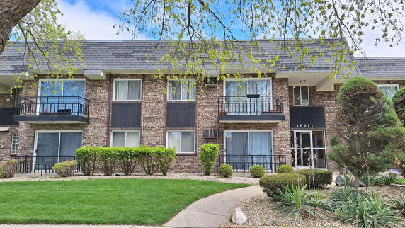 Front view of a two-story brick apartment building with balconies.