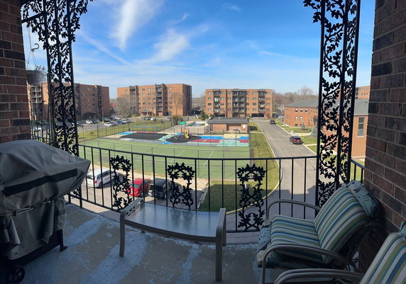 Wide angle view from a balcony showing a playground and multiple apartment buildings.