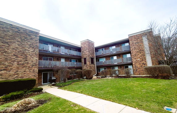 Front view of a brick residential apartment building with multiple floors and balconies.