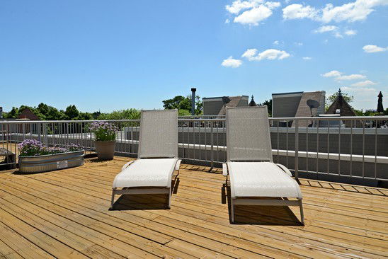 Rooftop with wooden decking and two lounge chairs.