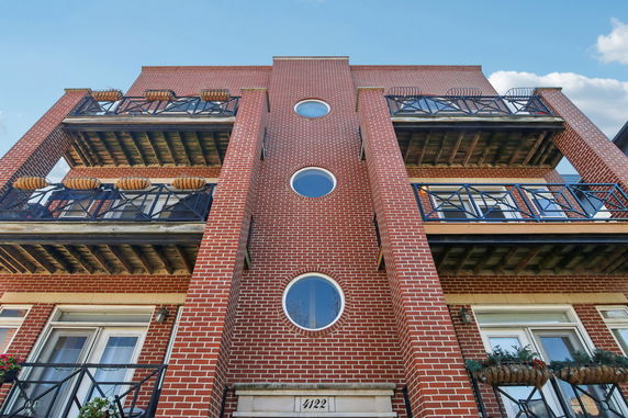 Front view of a brick multi-story building with balconies.