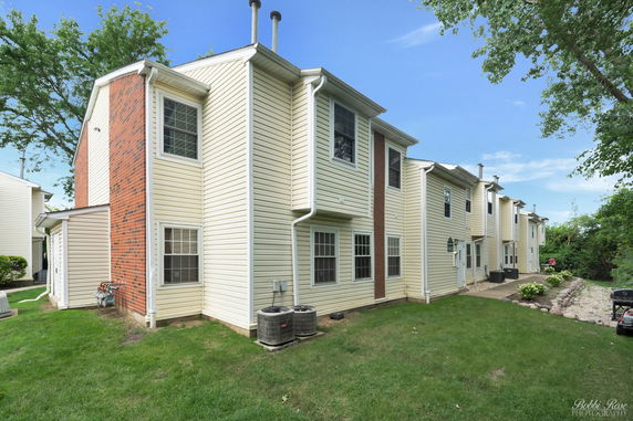 Rear view of a multi-story residential building with brick and siding exterior.