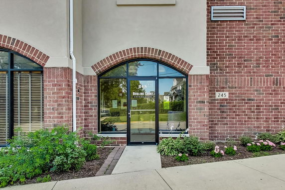 Front view of a building entrance with brick exterior and arched glass door.