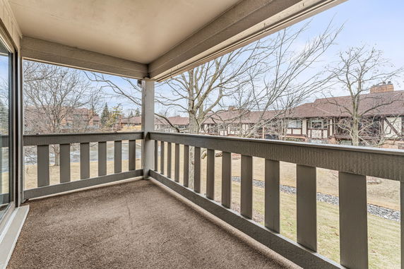 View from a covered balcony overlooking adjacent buildings and trees.
