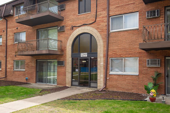 Front view of a multi-story brick apartment building with balconies.