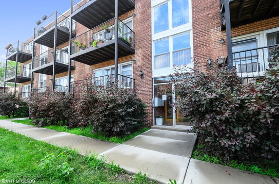 Front view of a multi-story brick apartment building with balconies.