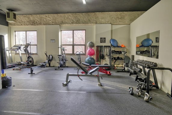 Room equipped with gym exercise equipment including weights and cardio machines.