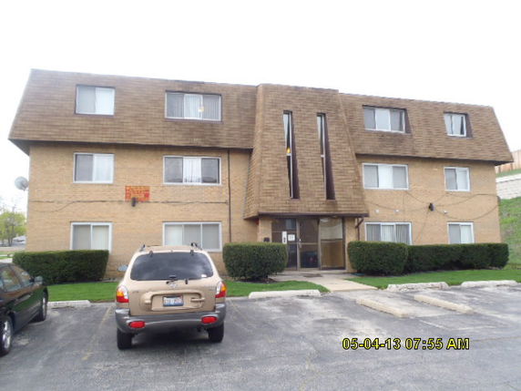 Front view of a three-story apartment building with a parking area.