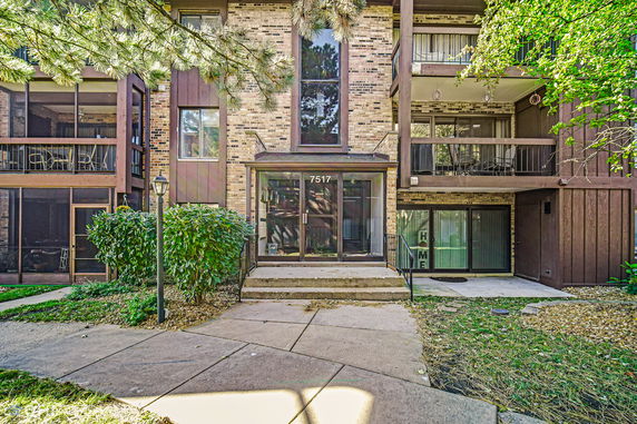Front view of a multi-story residential building with balconies and a glass entrance.
