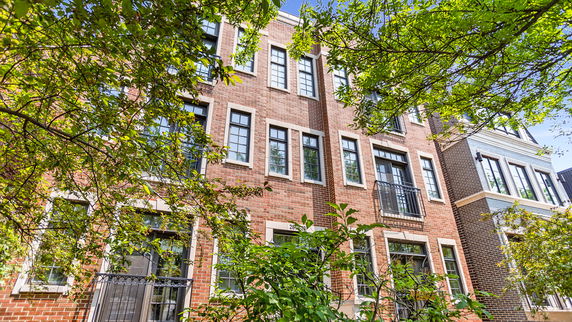 Front view of a multi-story brick building with large windows.