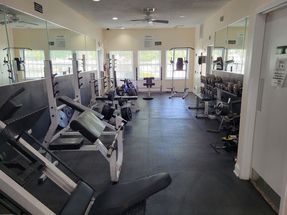 Interior view of a gym with weightlifting equipment and mirrors.