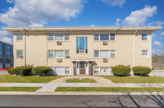 Front view of a three-story apartment building with a flat roof and multiple windows.