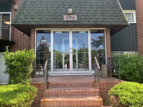 Front view of a building entrance with a brick staircase and glass doors.