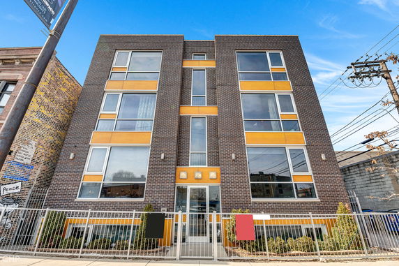 Front view of a modern, multi-story brick building with large windows and yellow accents.