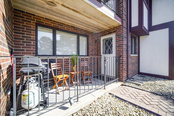 Front view of a brick patio with chairs and a grill.