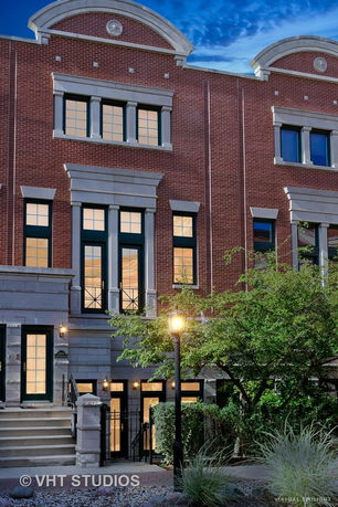Front view of a multi-story townhouse with brick facade and large windows.