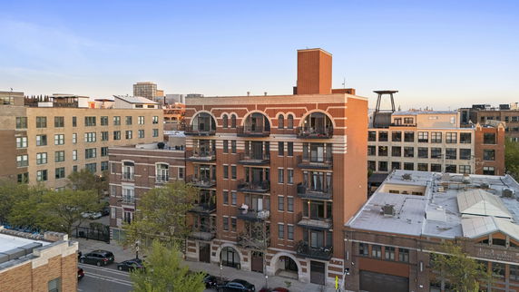Front view of a multi-story brick apartment building with balconies.