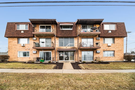 Front view of a three-story apartment building with balconies.