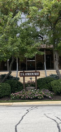 Front view of a building entrance with stairs and a sign reading '2 S. Atrium Way'.