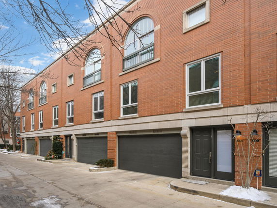 Front view of a multi-story brick townhouse with multiple garages.