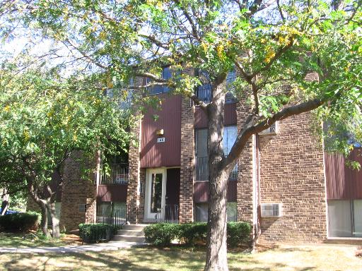 Front view of a multi-story building with brick and wood paneling.