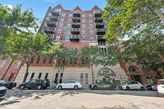 Front view of a multi-story brick building with balconies and arched main entrance.
