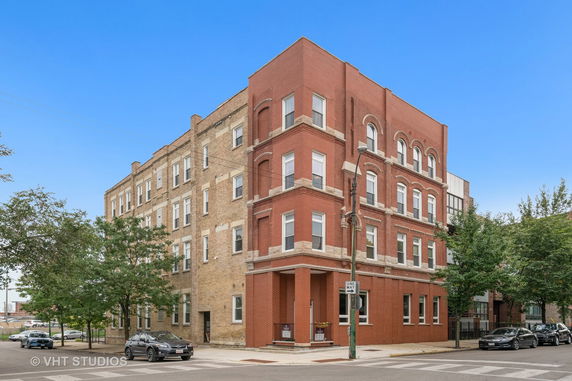 Front view of a multi-story brick building on a street corner.