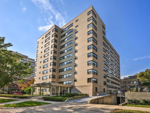 Front view of a multi-story apartment building with numerous windows and a covered entrance.