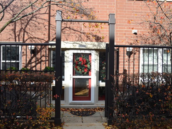Front view of a building entrance with a brick facade and a decorative wreath on the door.
