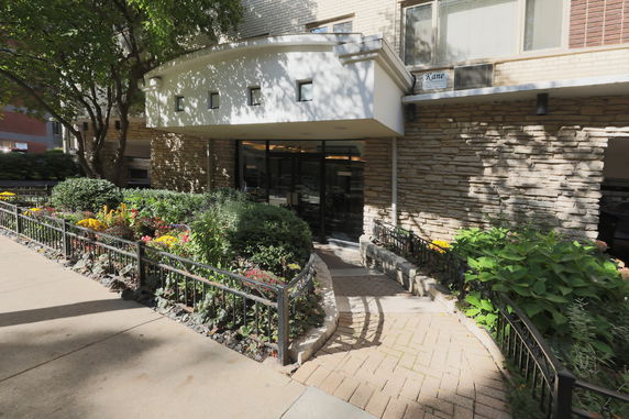 Front view of a building entrance with a stone exterior and landscaped garden.