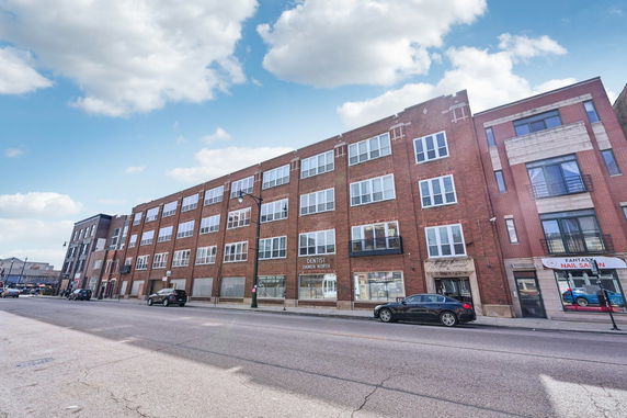 Front view of a multi-story brick building with large windows.