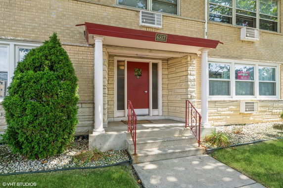 Front view of a building entrance with pillars and a red door.