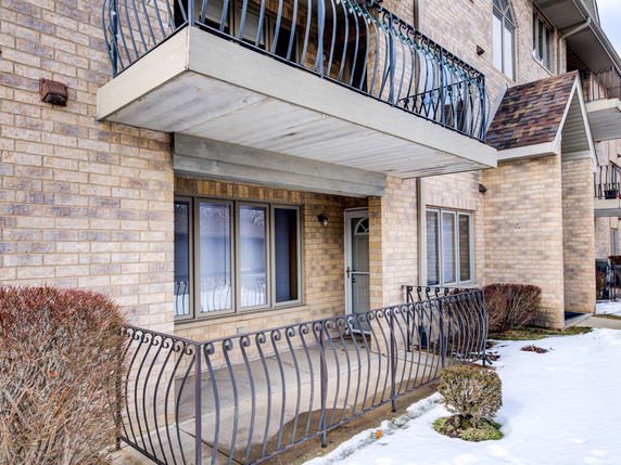 Front view of a multi-story brick building with balconies and iron railings.