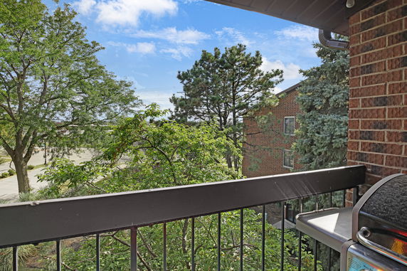 View from a balcony showing trees and a nearby building.