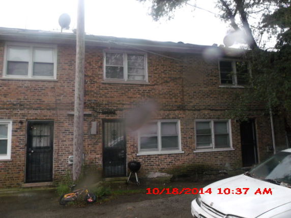 Front view of a two-story brick house with multiple windows and metal doors.