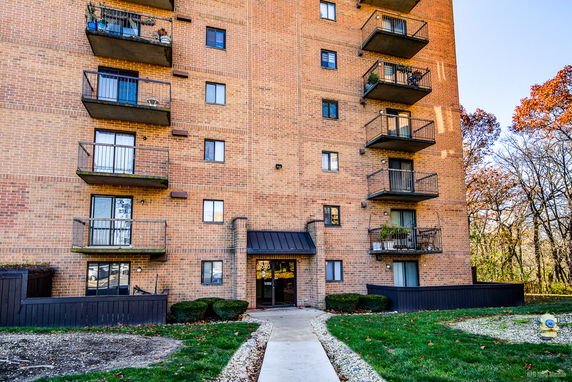 Front view of a multi-story brick apartment building with balconies.