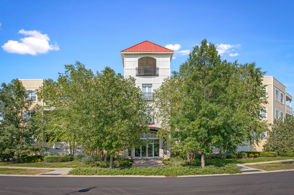 Front view of a multi-story building with a red roof and balconies.