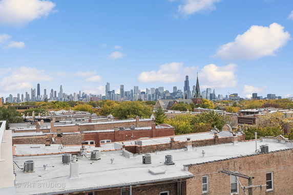 Panoramic view of a city skyline with multiple buildings and a church in the foreground.
